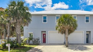 A two-story residential building with a red door, white garage doors, and a paved driveway. - 200 Yards toCocoa Beach, 4 bd, 3 1/2 Bath, Private Pool (Cocoa Beach)