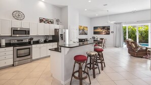 A modern kitchen with white cabinets, stainless steel appliances, and a central island with bar stools. - 200 Yards toCocoa Beach, 4 bd, 3 1/2 Bath, Private Pool (Cocoa Beach)