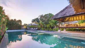 A clear swimming pool with lounge chairs and a thatched-roof structure. - The ultimate Bali beachside getaway at Villa Kaira Estate, a 7-bedroom luxury villa in Berawa, Canggu. The Estate offers daily breakfast, a full-time private chef, airport transfers, complimentary massages, housekeeping, and a dedicated driver. (North Kuta)