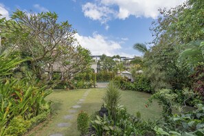 A lush garden with a variety of plants and a stone pathway leading to a building.