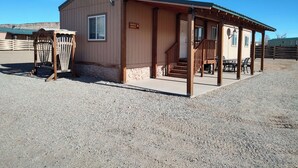A small, single-story building with a porch and a covered outdoor seating area. - Movie House (Thompson)