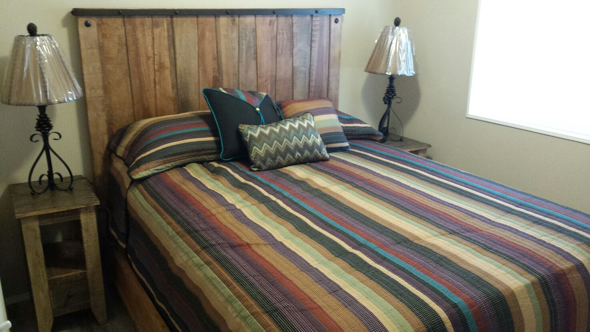 A bed with a striped bedspread and multiple pillows, flanked by two nightstands with lamps.