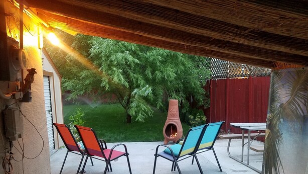 An outdoor patio with two chairs, a table, and a decorative fire pit.