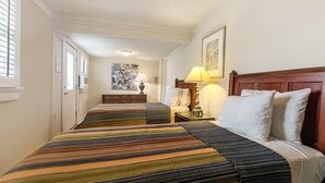 A hotel room with a large bed, a bedside table with a lamp, and a painting on the wall. - Walk to all the French Quarter attractions.  A great space to enjoy NOLA (New Orleans)