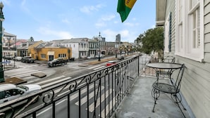 A balcony with a metal railing overlooking a street with cars and buildings. - Walk to all the French Quarter attractions.  A great space to enjoy NOLA (New Orleans)