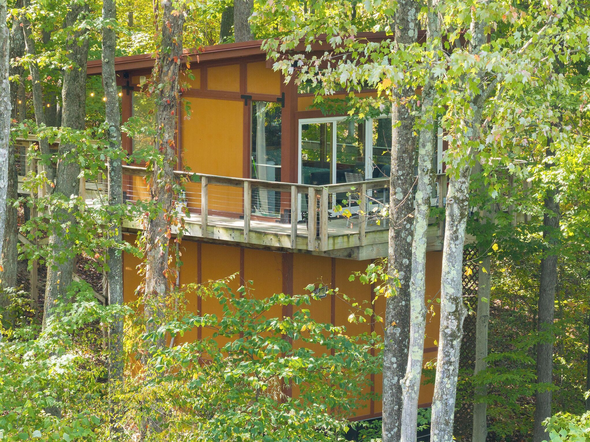 A wooden cabin with a balcony, surrounded by trees.