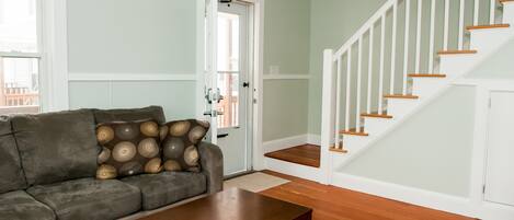 A living room with a sofa, coffee table, and a staircase with wooden steps and white railings.