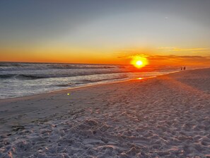 A beach with a sunset, waves, and footprints. - Seaside Serenity: Beach and Poolside Relaxation Just Steps Away! (Destin)