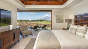 Camera da letto con un letto grande, una televisione, una scrivania e vista su un campo da golf.