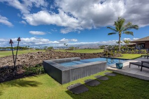 Une piscine bordée de pierres, une pelouse et une vue sur le paysage.