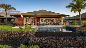 Una casa moderna con piscina, area relax esterna e un muro in pietra.
