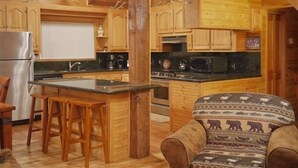 Interior de una cabaña de madera con cocina, comedor y una zona de estar acogedora.