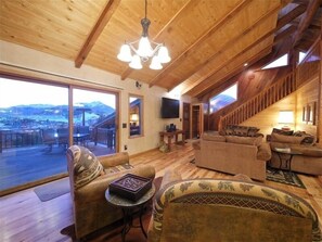 Relax in this inviting living area with a sofa set, TV, and scenic views through the sliding glass door.