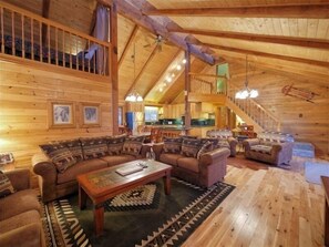 Cozy living area with a large sectional sofa, wooden coffee table, and staircase leading to an upper level.