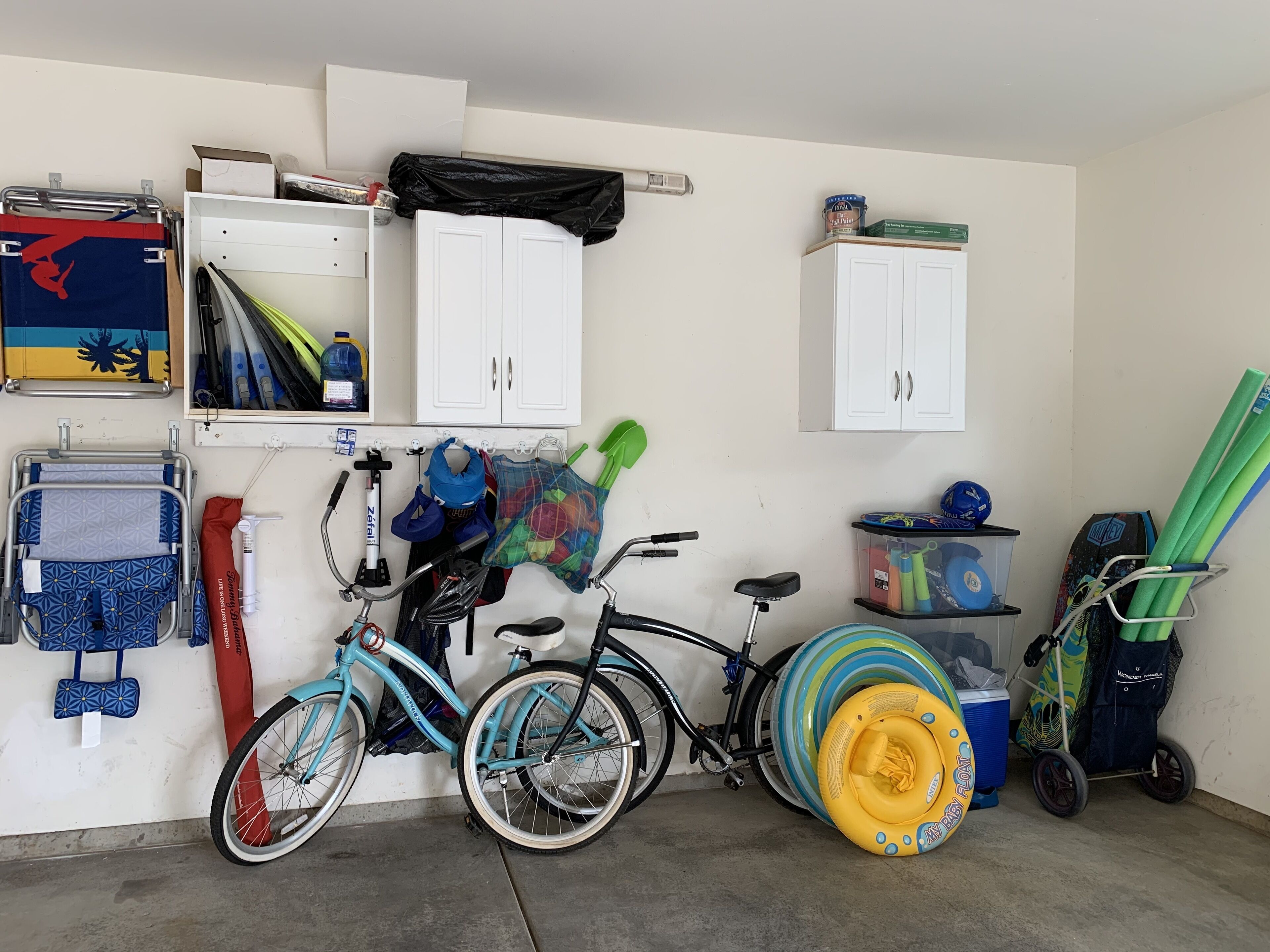 Un garage contenant deux vélos, un flotteur pour bébé et divers objets de rangement.