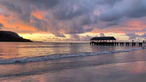 A beach scene with a pier extending into the water, a covered seating area, and waves approaching the shore. - Beautifully Furnished-Great for families 3 Bed, 2 1/2 Bath Nihilani, Princeville (Princeville)