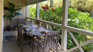 A covered outdoor dining area with a table set for two, surrounded by wooden chairs, and a potted plant to the left. - Beautifully Furnished-Great for families 3 Bed, 2 1/2 Bath Nihilani, Princeville (Princeville)