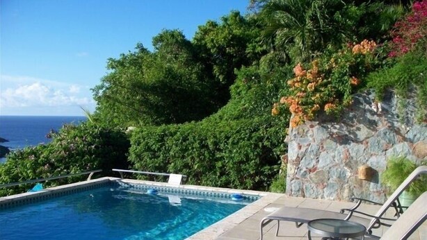 Ein Pool mit Liegestühlen und Blick auf den Ozean.