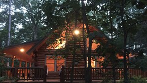 A log cabin with a porch and a staircase leading to the entrance.