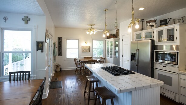 A kitchen with a central island, wooden flooring, white cabinetry, and a stainless steel refrigerator. - 3 acre Lake, Farm Animals Petting Zoo, Horses and Horseback Riding, Room to roam (Brownsburg)