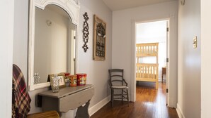 A hallway with a wooden floor, a bench, a chair, a table with decorative items, and a mirror. - 3 acre Lake, Farm Animals Petting Zoo, Horses and Horseback Riding, Room to roam (Brownsburg)
