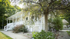 A white house with a porch, steps, and a garden with purple flowers. - 3 acre Lake, Farm Animals Petting Zoo, Horses and Horseback Riding, Room to roam (Brownsburg)