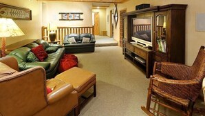 A cozy living room with a leather sofa, a wooden rocking chair, and a television on a wooden stand.