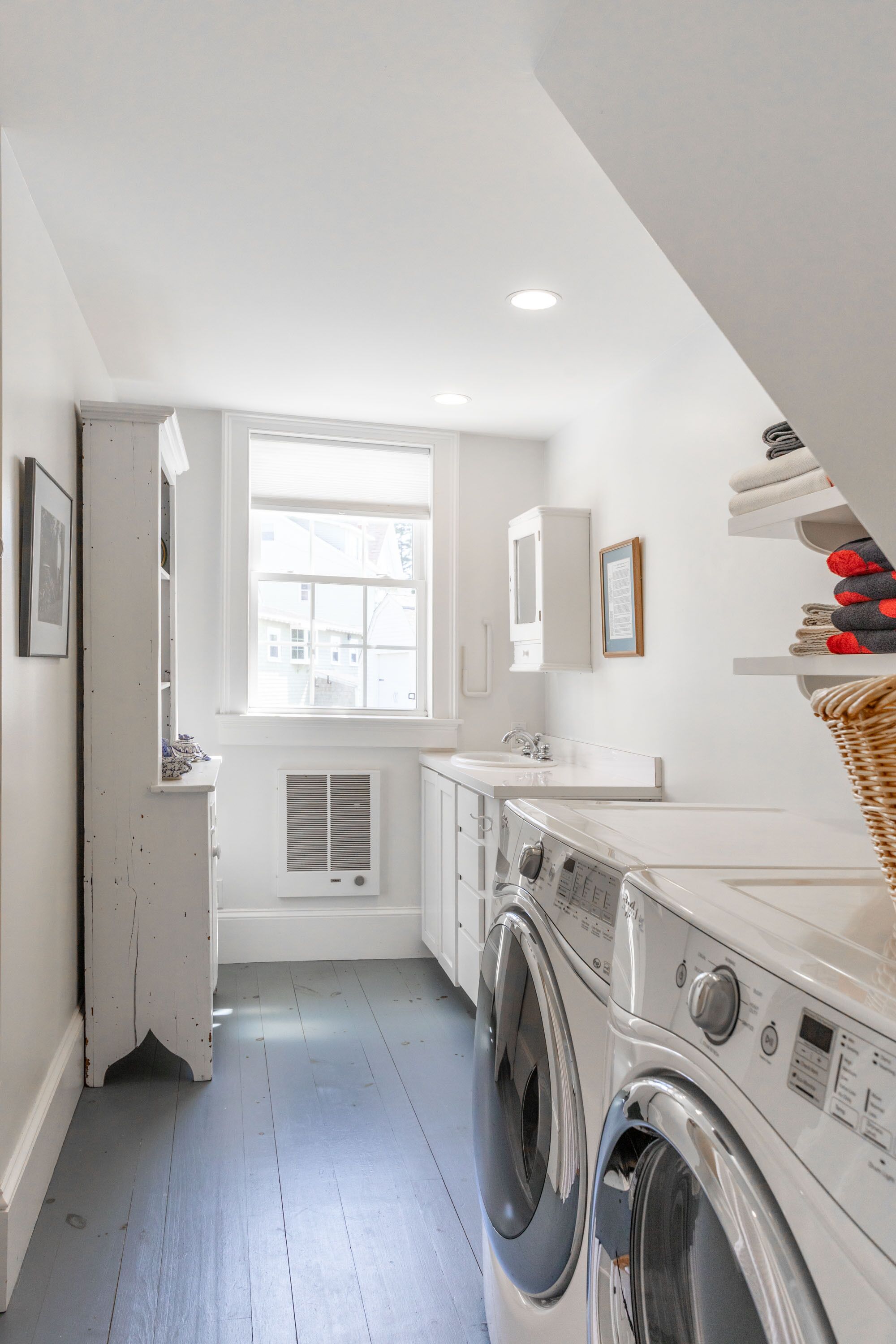 Une buanderie équipée d’un lave-linge, d’un sèche-linge et d’une fenêtre donnant sur des immeubles.