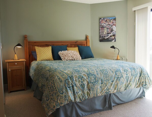 A bedroom with a bed, nightstands, and a wall-mounted lamp. - Beachfront Condo with Amazing Views, Comfort, and Fun for Everyone (Watsonville)