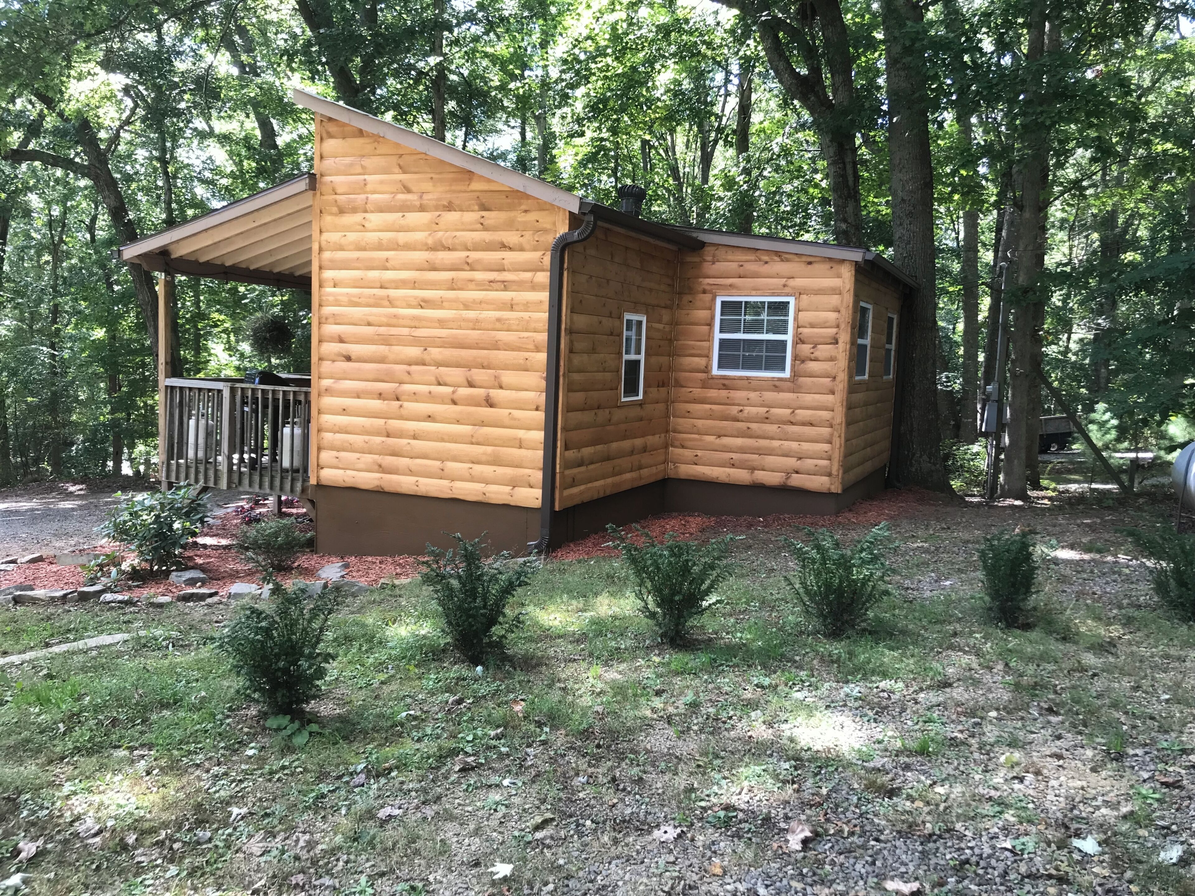 A wooden cabin with a porch, a small window, and a chimney.