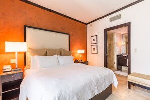 A hotel room with a large bed, two bedside lamps, a nightstand, a bench, and a bathroom visible through an open door. - Oceanview Penthouse, Private Rooftop w/ Hot Tub, Steps to Ocean (Miami Beach)