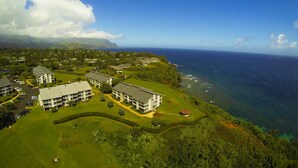 Eine Vogelperspektive eines Küstenresorts mit mehreren Gebäuden, saftig grünen Rasenflächen und freiem Blick auf den Ozean.