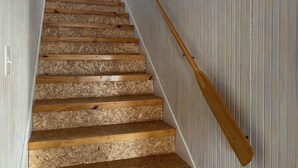 Una escalera de madera con barandilla que conduce a un piso superior.