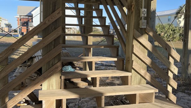 Una escalera de madera que conduce a un espacio cubierto con barandilla de metal.