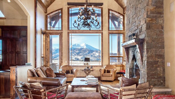 A cozy living room with a fireplace, leather furniture, and a view of a mountain.
