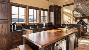 A spacious kitchen with large windows, a stone fireplace, and a view of the mountains.