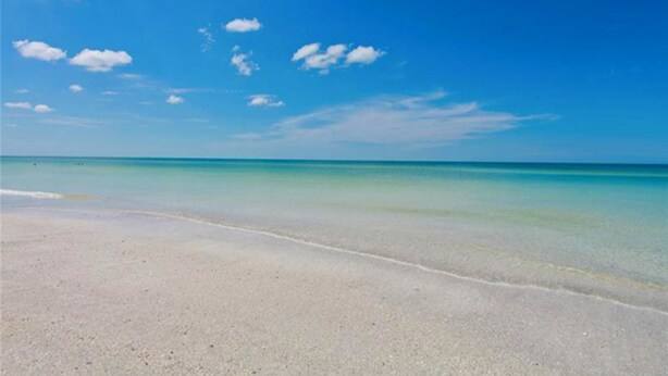 Een strand met helder turquoise water en een zandstrand.