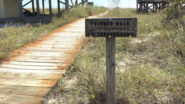 A wooden boardwalk leading to a beach house with a sign indicating it is a private walk. - Family Friendly, Ft Morgan Beach House (Gulf Shores)