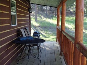Enjoy dining or socializing on the covered porch with a table and two chairs.