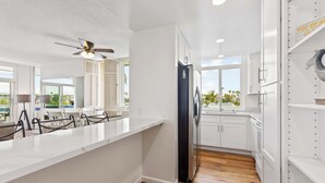 A modern kitchen with white cabinetry, a black refrigerator, and a wooden floor.
