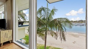 A room with a large window overlooking a beach and marina.