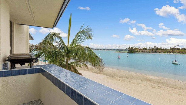 A balcony with a view of a beach and calm water.