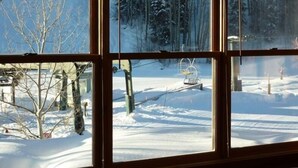 A view through a window of a snowy landscape with a ski lift and trees.