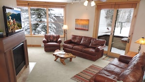 A living room with a fireplace, leather sofas, a coffee table, and a TV.