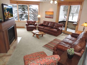 A living room with a fireplace, leather sofas, a coffee table, and a TV.