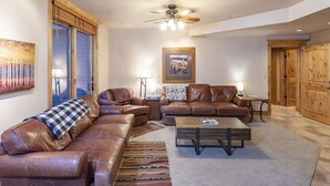 A living room with leather sofas, a wooden coffee table, and a ceiling fan.