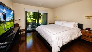A bedroom with a large bed, a TV, a desk, and a view of a golf course through the window. - Charming Napa condo with 3 beds, garden view at Silverado (Napa)