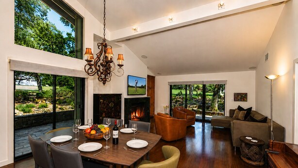 A spacious living area with a dining table set for a meal, a fireplace, and a large window overlooking a garden. - Charming Napa condo with 3 beds, garden view at Silverado (Napa)