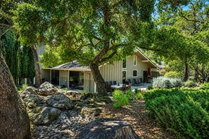 A house with a patio, surrounded by trees and rocks.