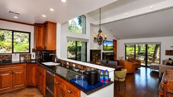 A spacious kitchen with wooden cabinets, a large island, and a dining area with a view of the outdoors.